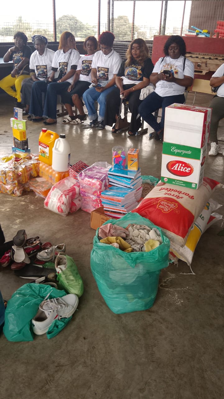 Team members seated beside food, clothing and school supplies ready to hand out