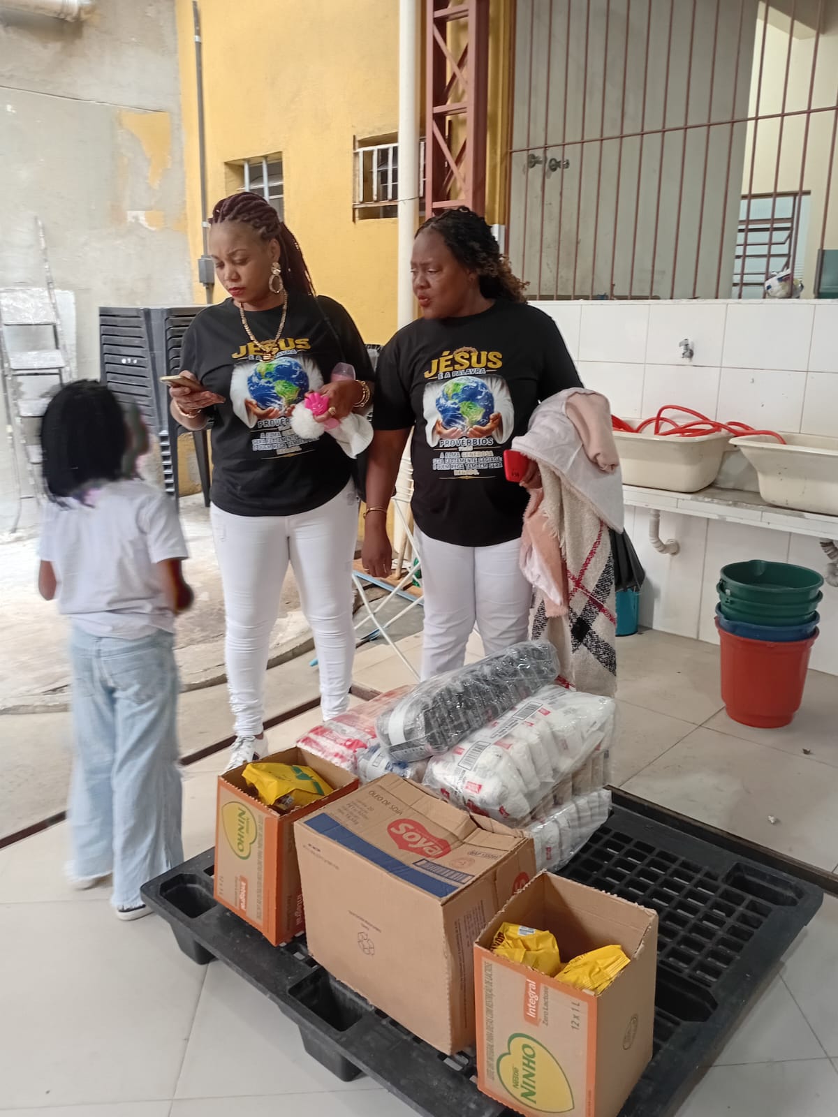Volunteers organising food parcels while a child looks on