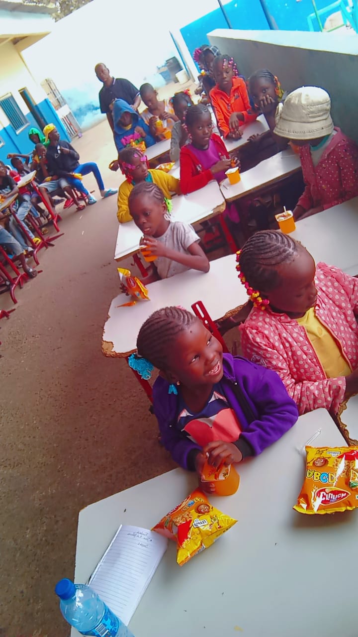 Children seated at tables enjoying snacks and drinks during an outreach meal