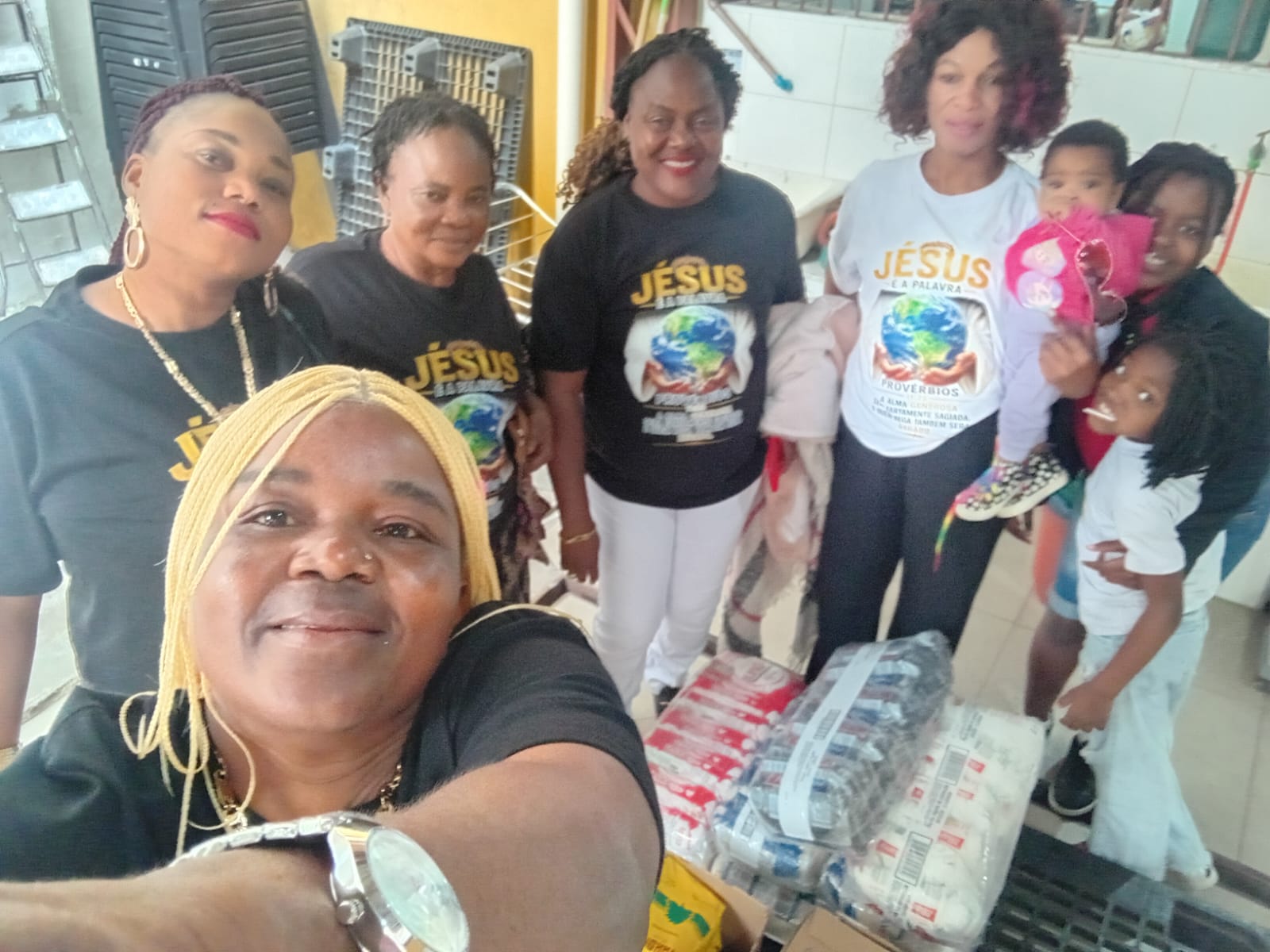 Group of volunteers and children gathered around food donations