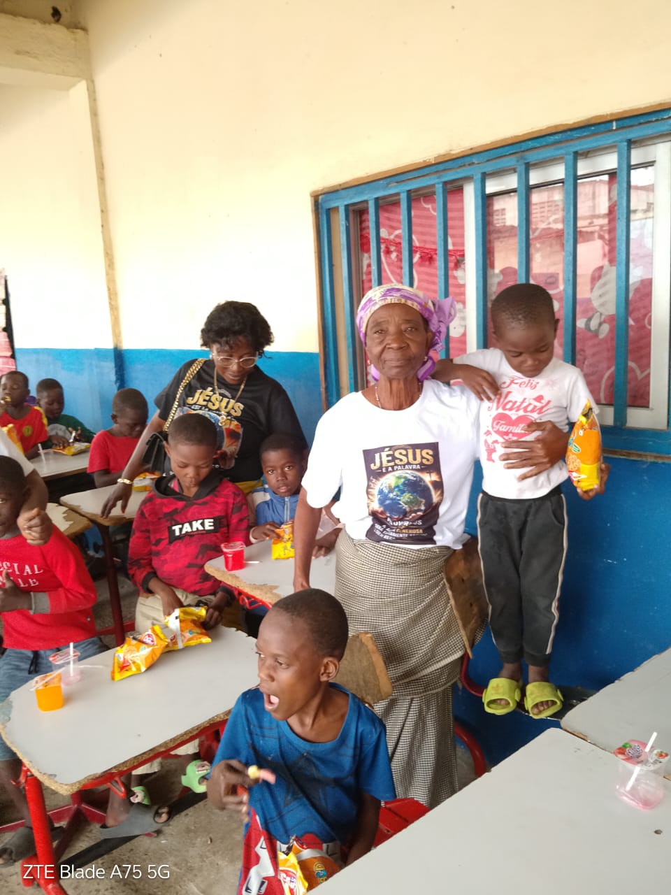 A grandmother and children with snacks inside a community classroom