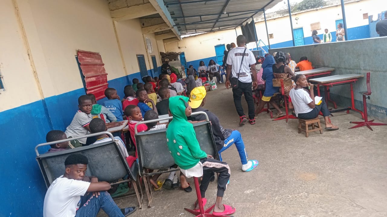 Children seated at school desks receiving meals and refreshments