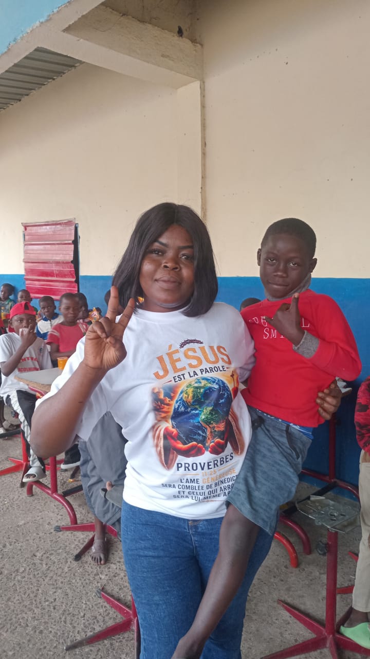 A volunteer holding a smiling child during a school outreach visit