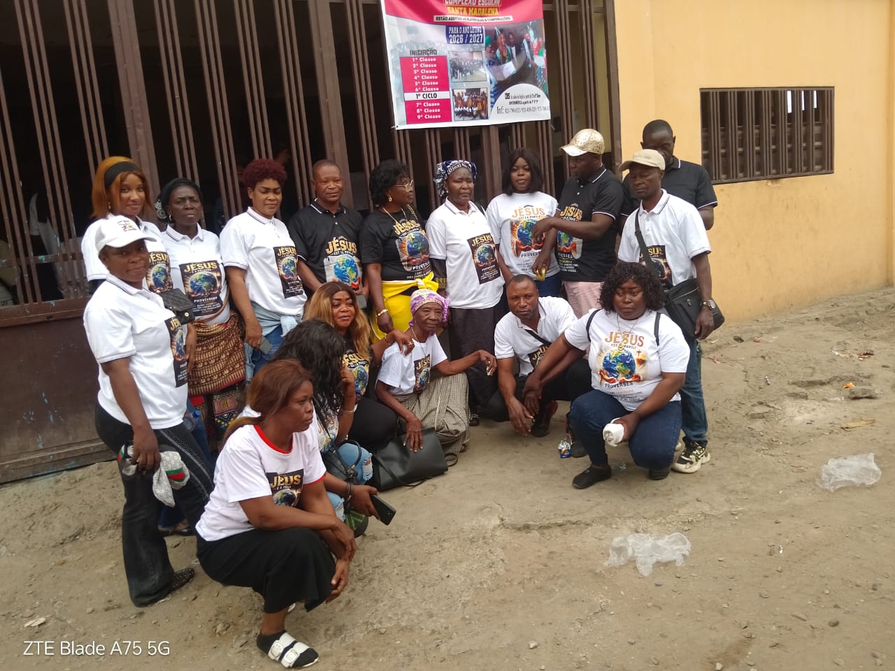 Volunteers in ministry shirts posing together outside the school complex